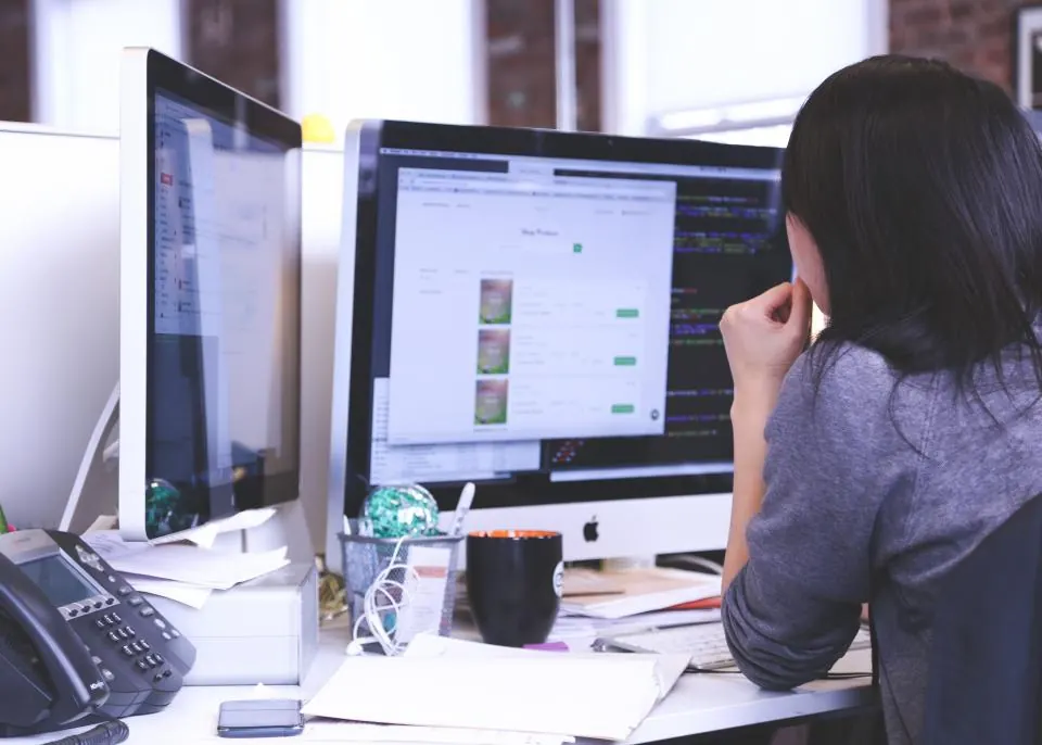 Analyst working at two monitors in an office