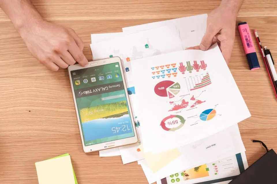 Buyer reviewing printed charts and a phone at a desk