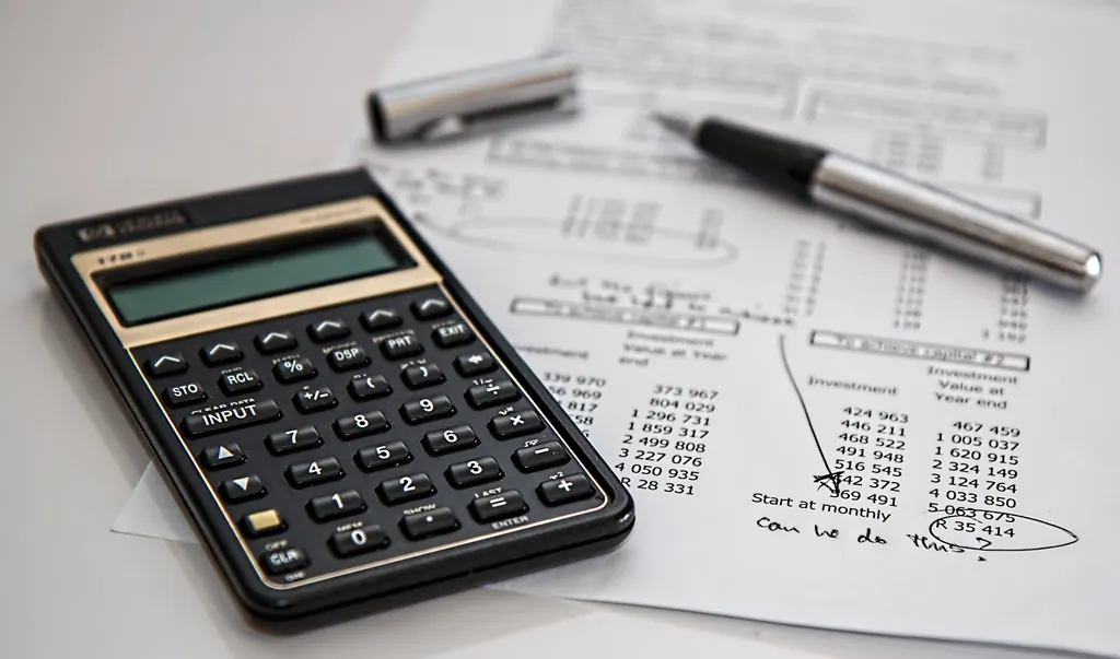 Calculator and pen resting on a sheet of figures