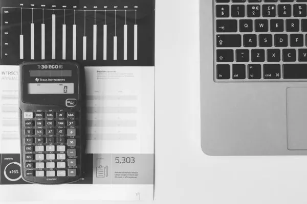 Calculator resting on a printed report beside a laptop