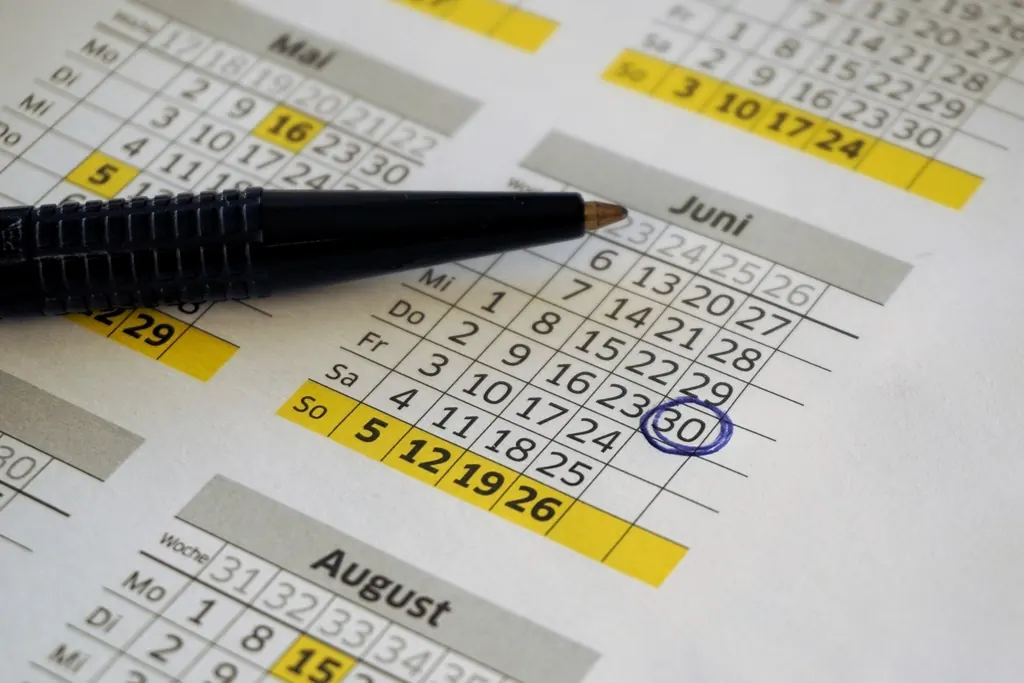 Pen pointing at dates on a printed calendar page