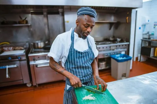 Chef in an apron chopping food in a commercial kitchen