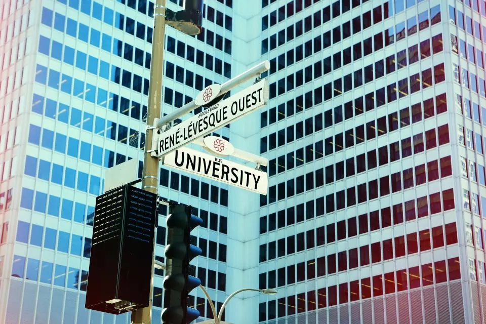Street signs at a city intersection in front of an office tower