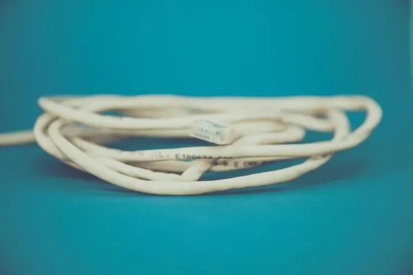 Coiled white network cable on a teal background