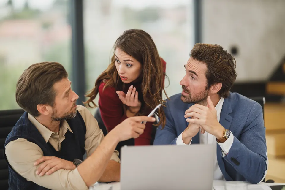 Consultant discussing a plan with two clients at a laptop