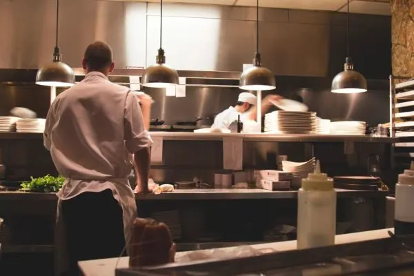 Cooks working under lamps in a restaurant kitchen