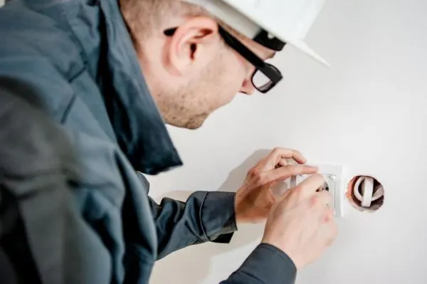 Electrician fitting a socket box into a wall