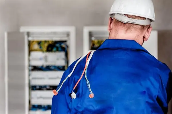 Electrician in a hard hat working at a control panel