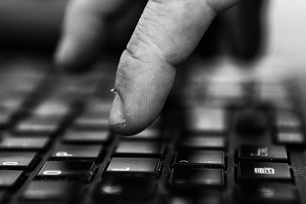 Close view of a finger typing on a laptop keyboard