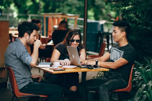 Four people meeting around a cafe table with a laptop