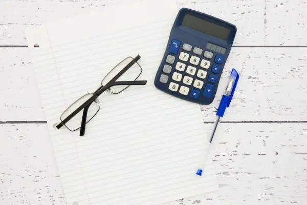 Glasses, calculator and pen on a white desk