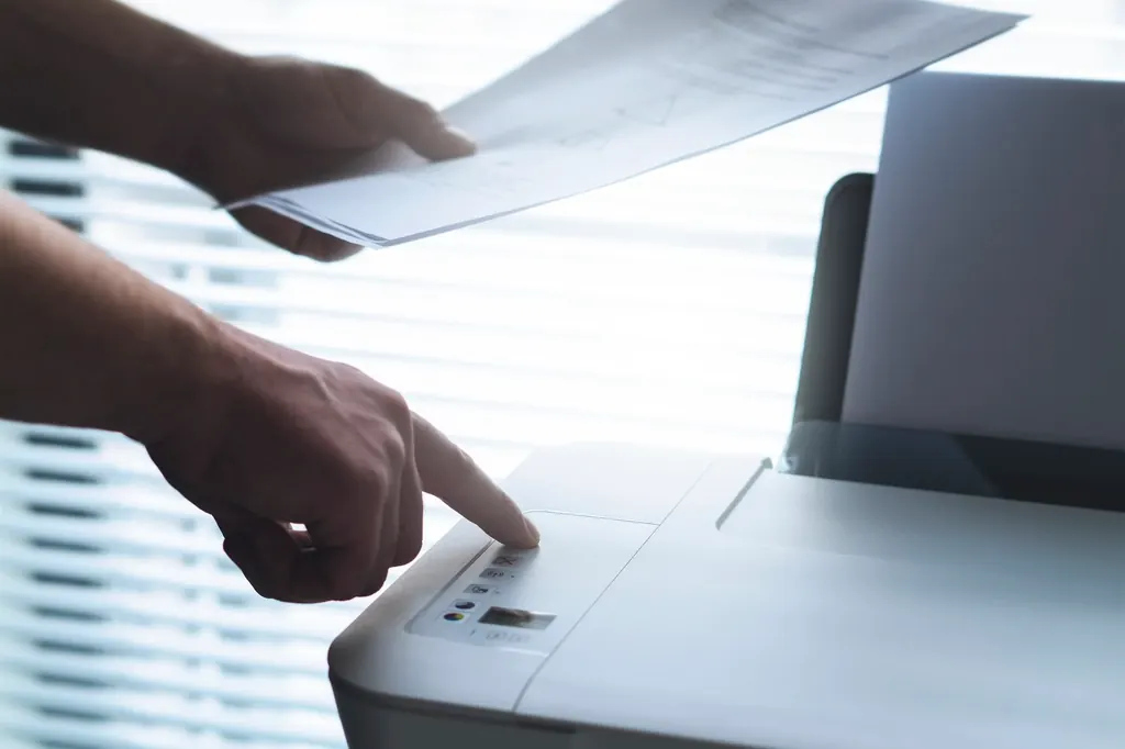 Hand feeding a sheet of paper into an office printer