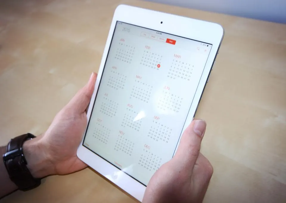 Hand holding a tablet showing a calendar app