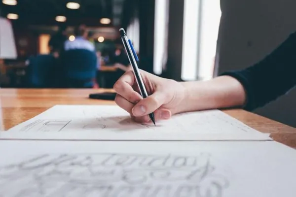 Hand sketching on a sheet of paper at a desk