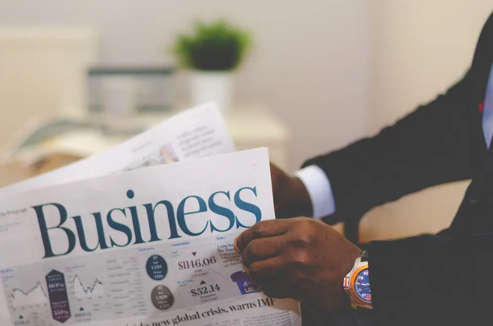 Hands holding open the business section of a newspaper