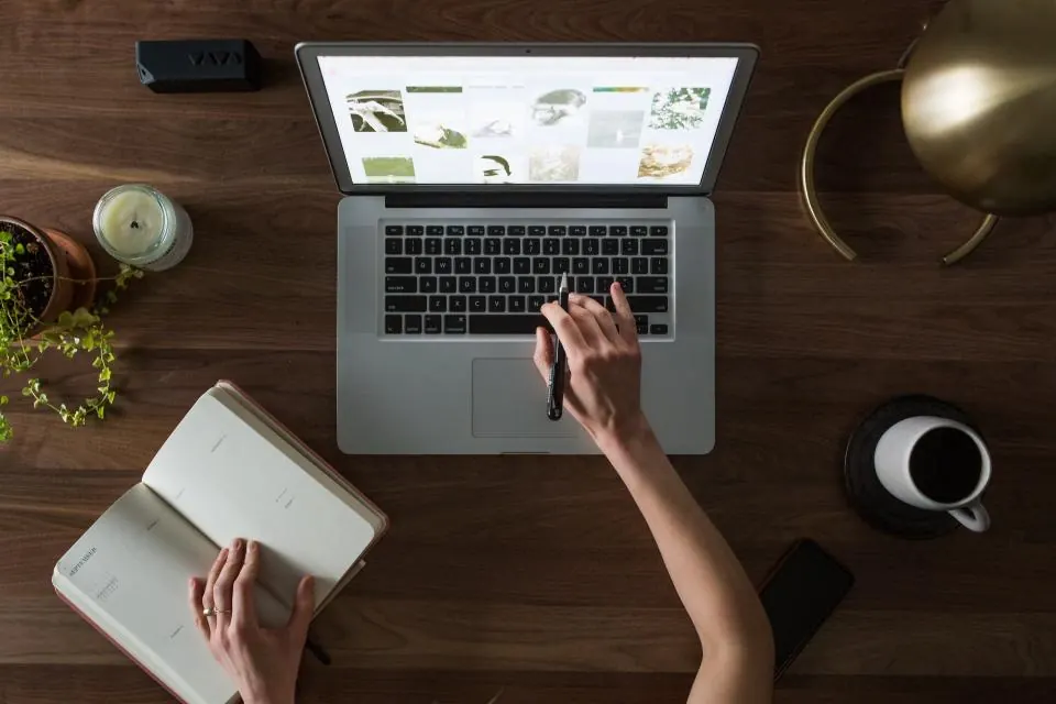 Top view of a laptop, notebook and coffee on a wooden desk