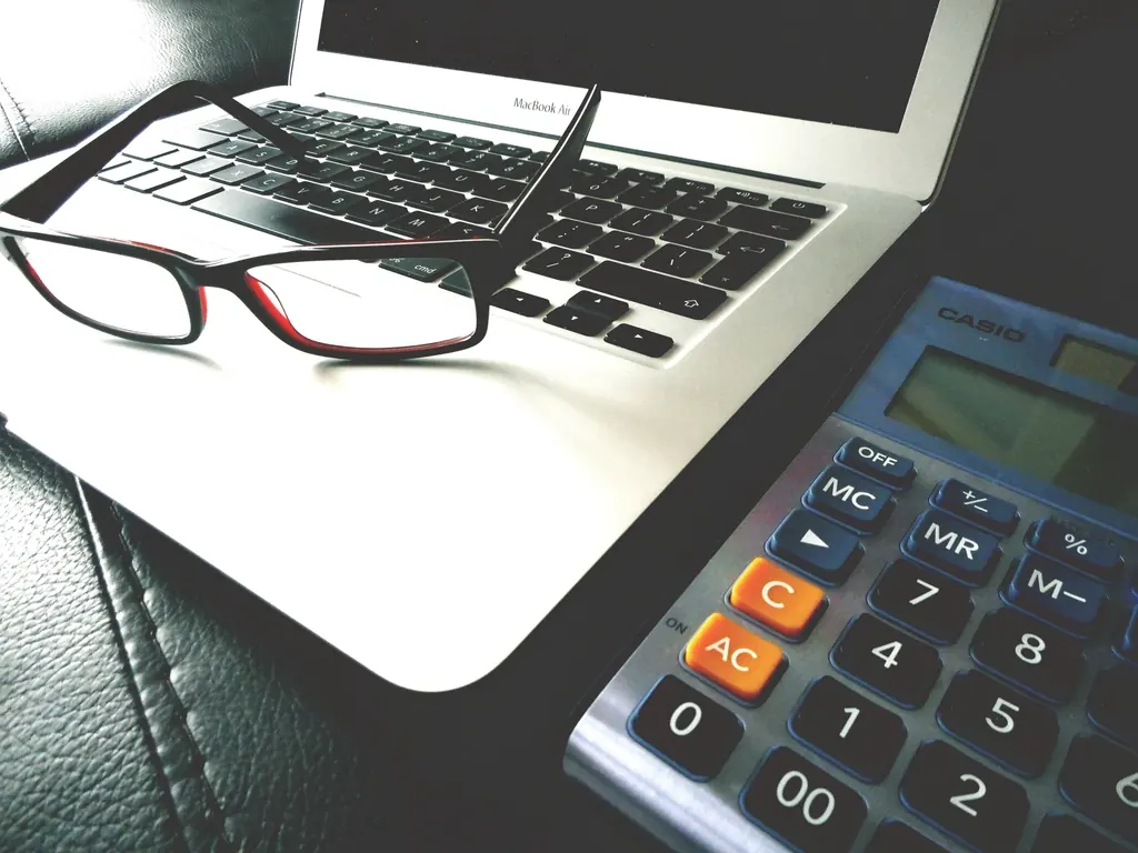Laptop, reading glasses and a calculator on a desk