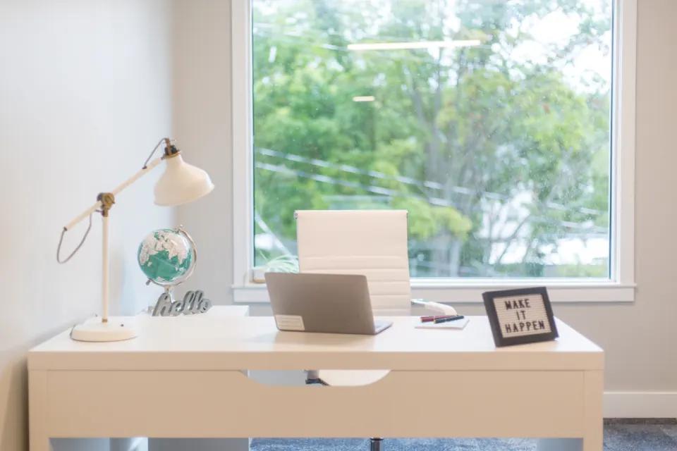 Laptop on a bright home office desk beside a window