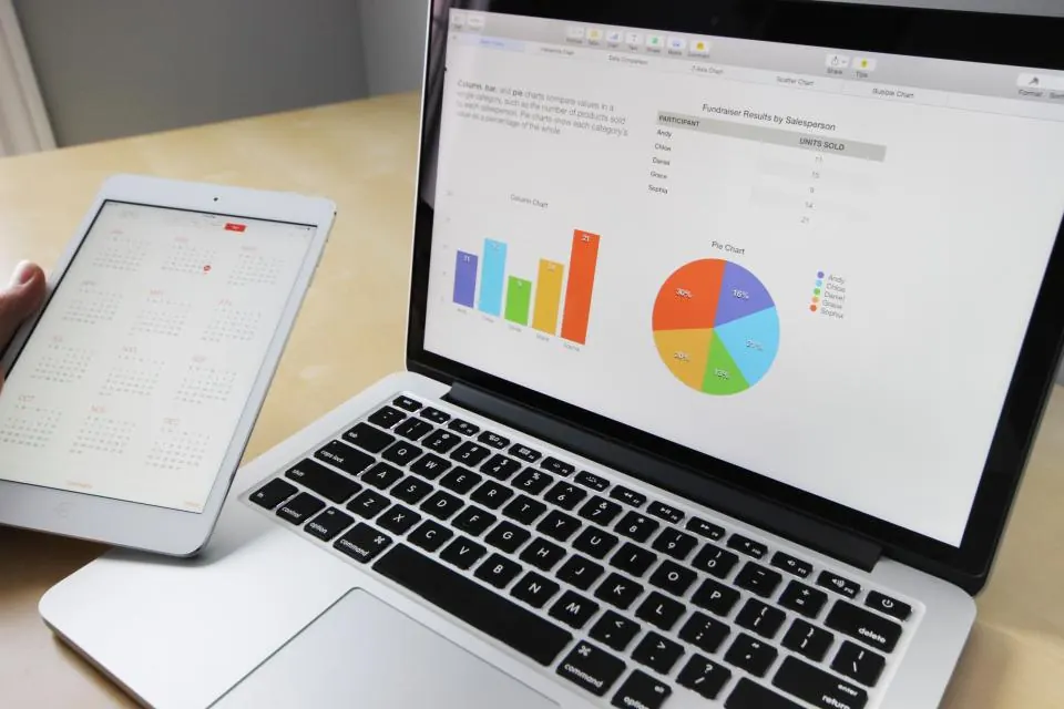 Laptop showing sales charts beside a tablet on a desk