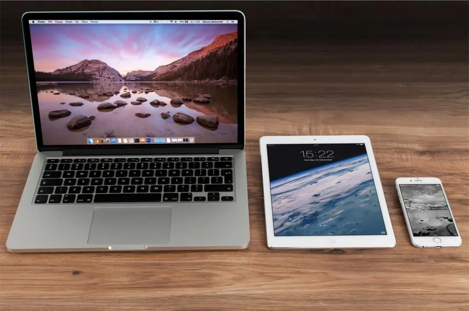 Laptop, tablet and phone side by side on a wooden desk