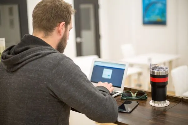 Man in a hoodie working on a laptop at a table
