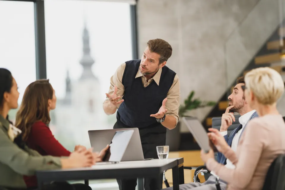 Man presenting to colleagues around a meeting table