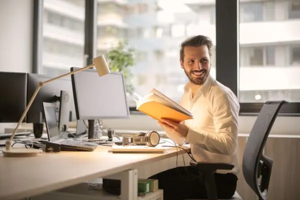 Man reading notes at his office workstation