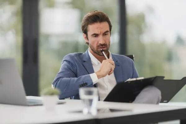 Man signing a document on a clipboard at his desk