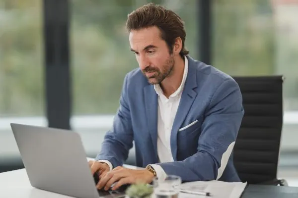 Man working on a laptop at a bright office desk