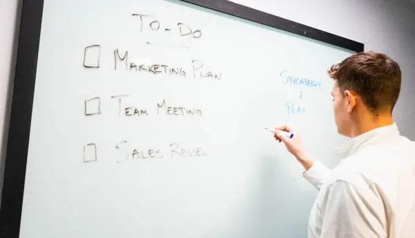 Man writing a to-do list on a whiteboard
