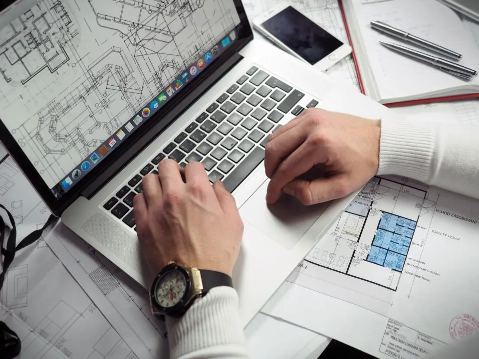 Manager comparing printed sheets with figures on a laptop