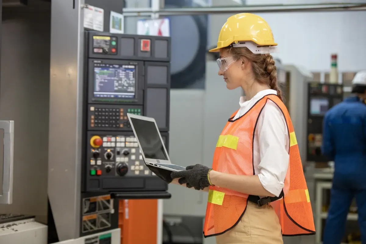 Machine operator in safety gear working at an industrial production line