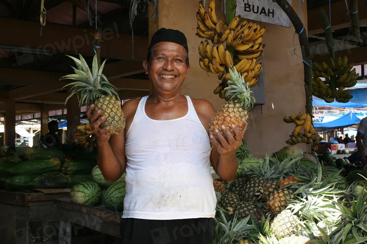 Smiling market stall owner holding pineapples