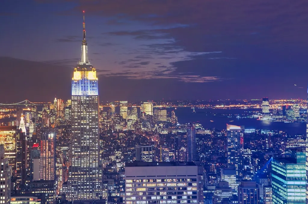 Empire State Building lit up over the Manhattan skyline at night