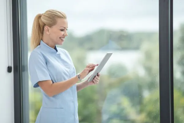 Nurse using a tablet beside a window