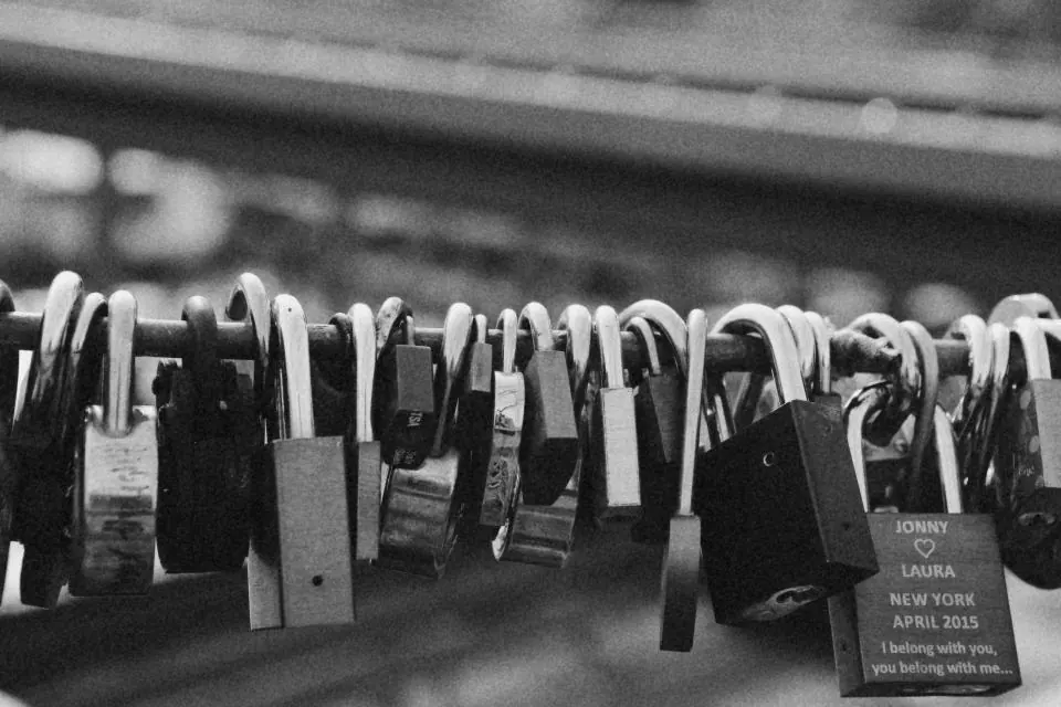 Padlocks locked onto a railing in black and white