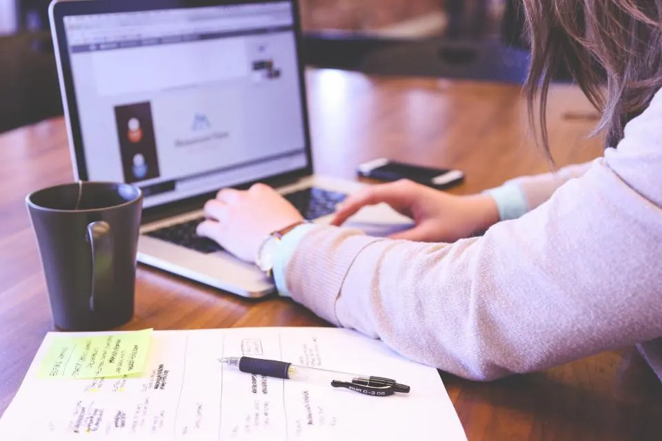 Person working at a laptop with coffee and handwritten notes