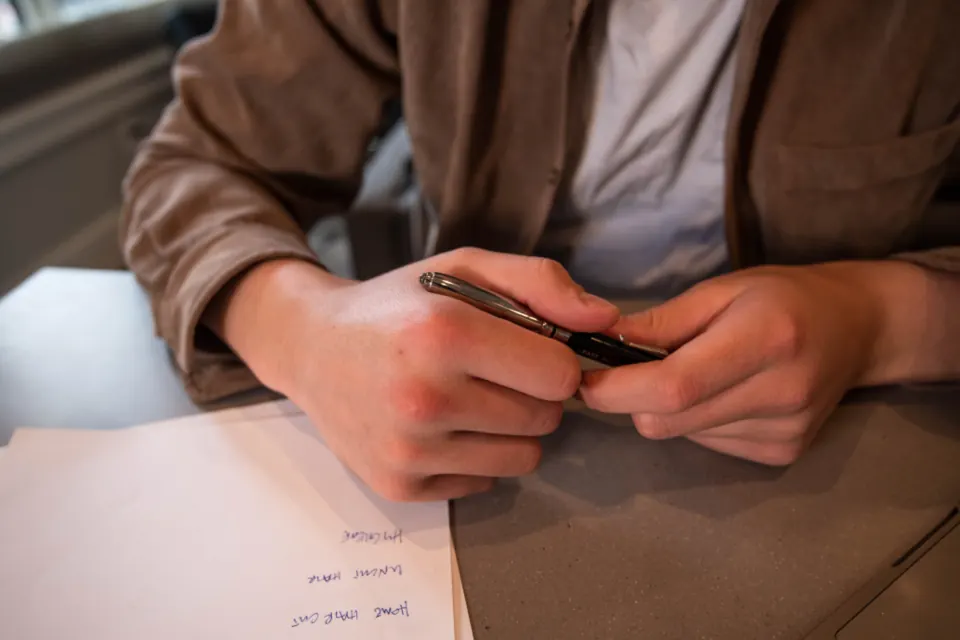Person holding a pen over paperwork at a desk