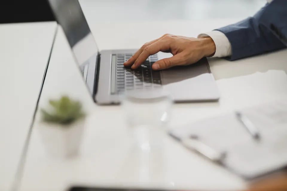 Person typing on a laptop at a white desk