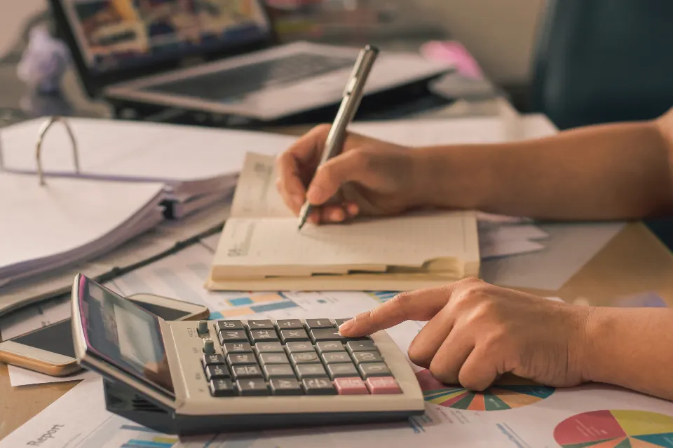 Person working through figures with a calculator and notebook