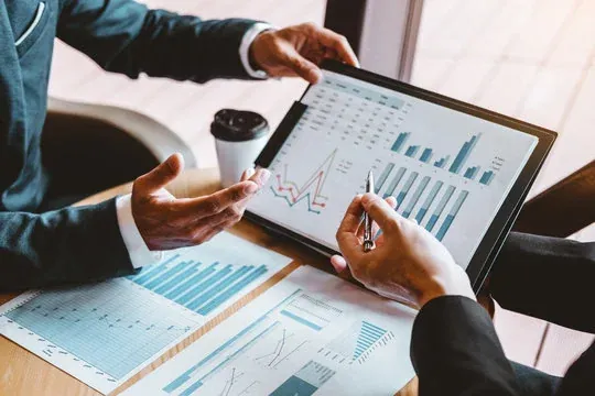 Hands holding a tablet showing a business dashboard with charts