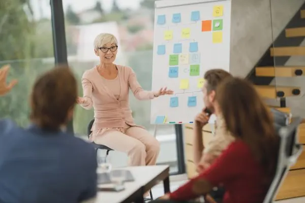 Presenter talking to a team beside a sticky note board