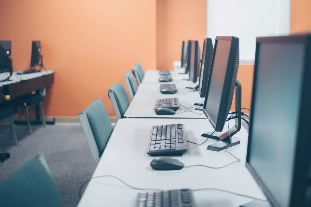 Row of computer workstations along a long office desk