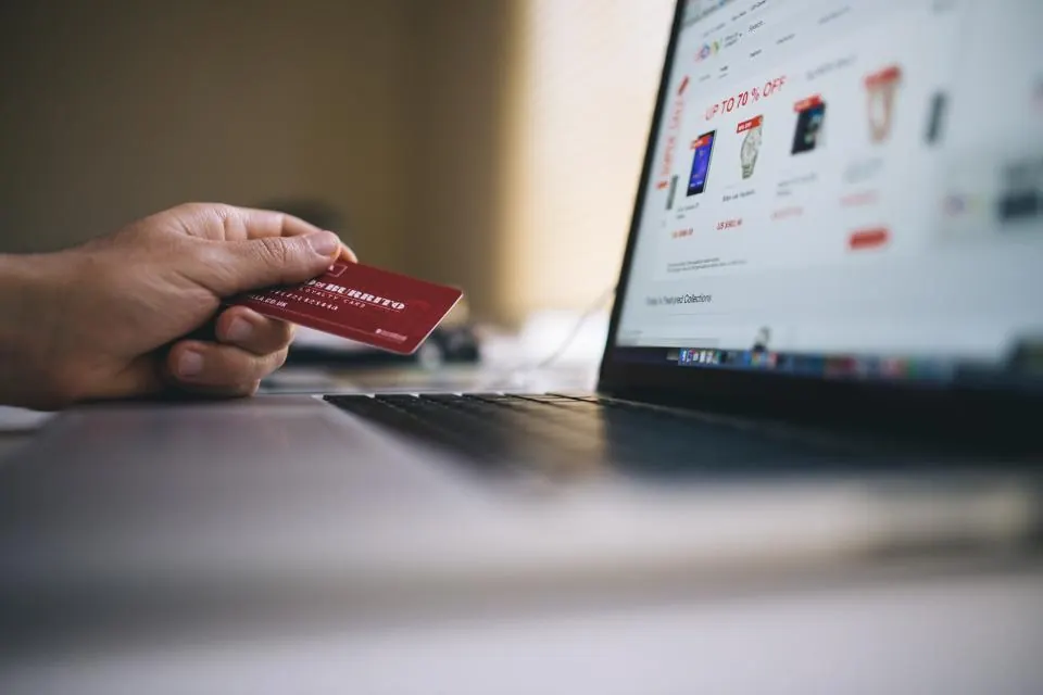 Shopper holding a payment card in front of an online store
