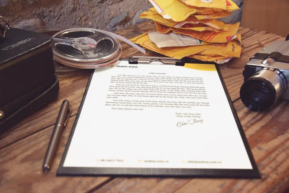 Signed letter on a clipboard beside envelopes on a desk