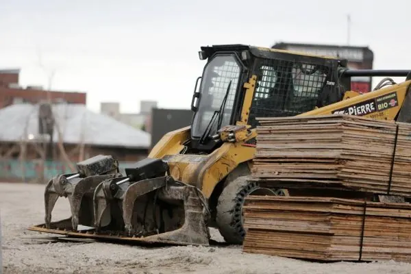 Skid steer loader parked beside stacks of lumber