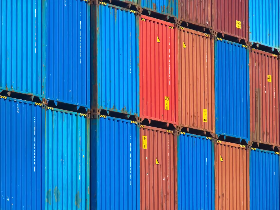 Stacked blue and red shipping containers at a port