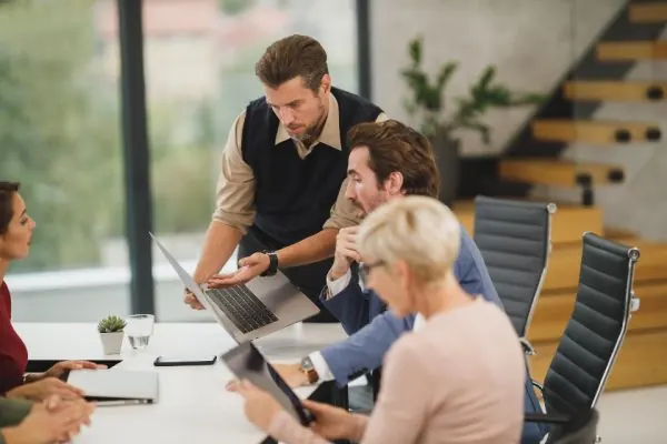 Team leaning over a laptop in a meeting room