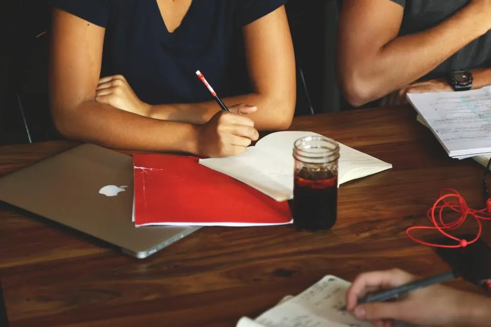 Team taking notes around a meeting table with a laptop