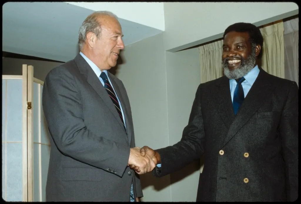 Two colleagues shaking hands across a table in a conference room